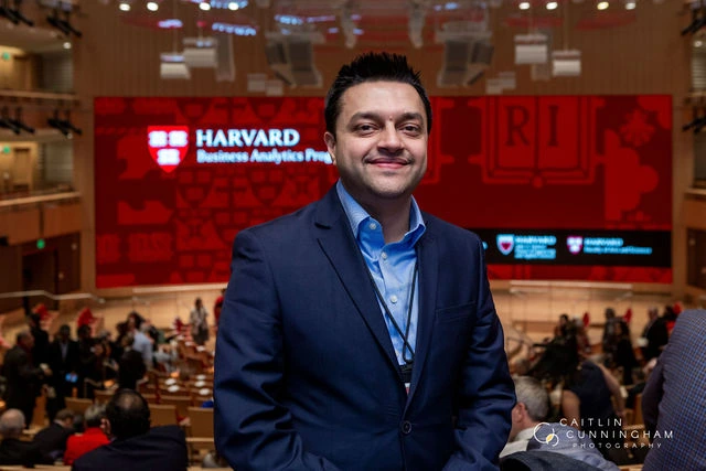 Parth Pandya standing in an auditorium with Harvard Business Analytics Program signage behind him.