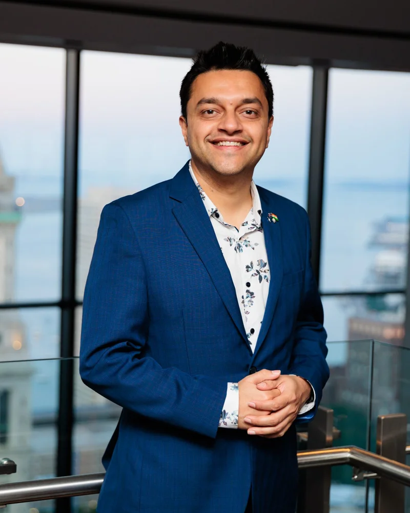 Parth Pandya smiling in a blue jacket, with his hands clasped.